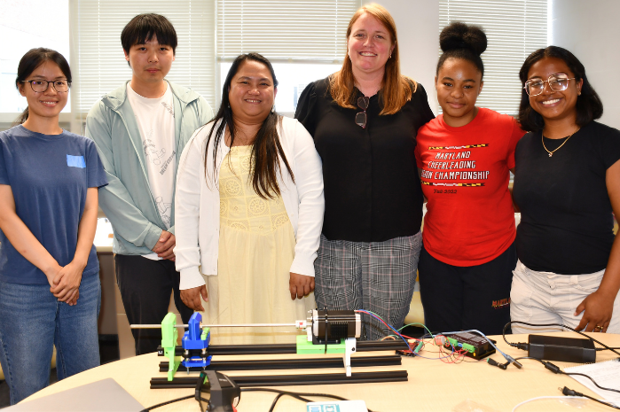 RET teachers with some of the UMD students and faculty who mentored them. They are standing in front of a table with the RET research projects.